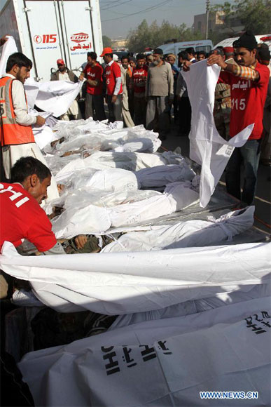 Pakistani rescuers arrange dead bodies of illegal immigrants for identification, who were killed near the border with Iran, in southern Pakistani port city Karachi, on Dec. 23, 2012. Some unknown gunmen killed at least 10 people on Friday evening as they attacked a passenger vehicle in Pakistan's southwestern province of Baluchistan, local media reported. (Xinhua/Arshad)