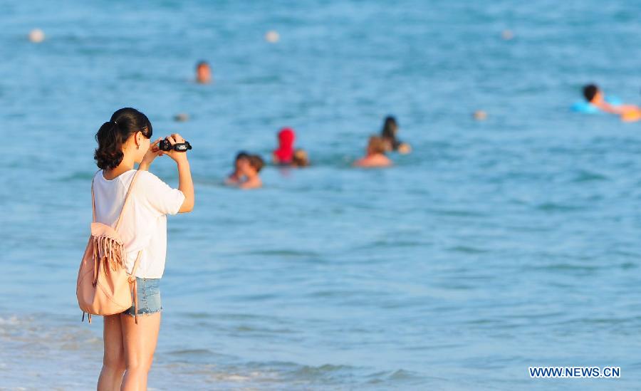 A visitor shoots a film at a beach in Sanya, a famous tourism city in south China's Hainan Province, Dec. 25, 2012. Many tourists chose to visit Sanya for its warm weather. (Xinhua/Hou Jiansen) 