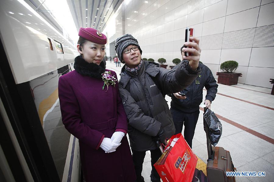 A passenger uses his mobile phone to take a group photo with a stewardess before boarding bullet train G801 to leave for Guangzhou, capital of south China's Guangdong Province, at the Beijing West Railway Station in Beijing, capital of China, Dec. 26, 2012. (Xinhua/Wang Shen) 