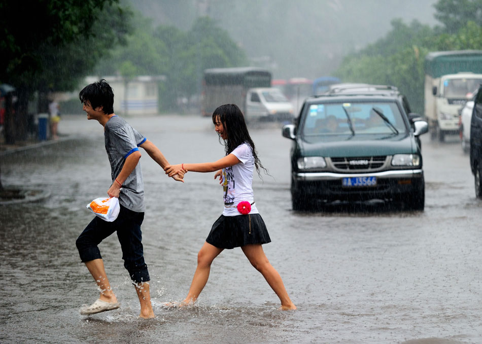 A pair of happy lovers walks hand in hand to cross a flooded street in southwest China's Chongqing municipality, May 21, 2012. (Xinhua/Li Jian) 