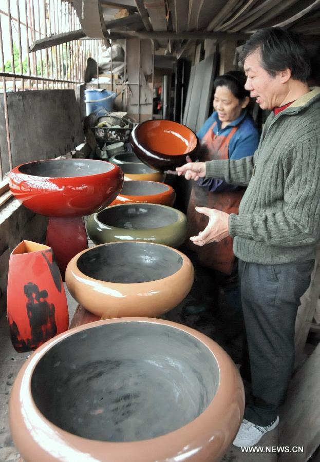 Craftworkers Lin Youxin (R) and Zeng Jingxiu (L) examine bodiless lacquerware works in Fuzhou, capital of southeast China's Fujian Province, Dec. 26, 2012. (Xinhua/Lin Shanchuan)