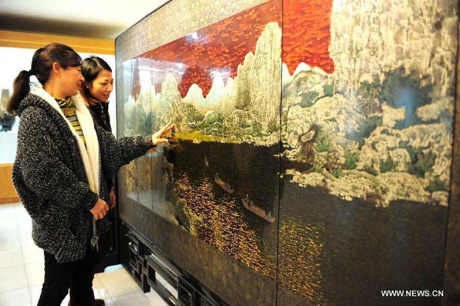 Visitors view a lacquer painting table screen at a conservation base for bodiless lacquerware in Fuzhou, capital of southeast China's Fujian Province, Dec. 27, 2012. (Xinhua/Lin Shanchuan)