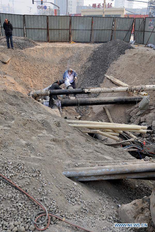 Workers repair the damaged pipelines at the collapsed section of the road intersection of Bingzhou North Road and Bingzhou East Street in Taiyuan, capital of north China's Shanxi Province, Dec. 27, 2012.