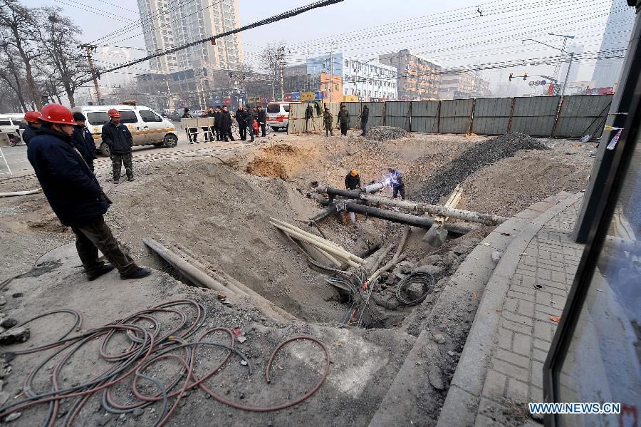 Workers check the damaged pipelines at the collapsed section of the road intersection of Bingzhou North Road and Bingzhou East Street in Taiyuan, capital of north China's Shanxi Province, Dec. 27, 2012. 