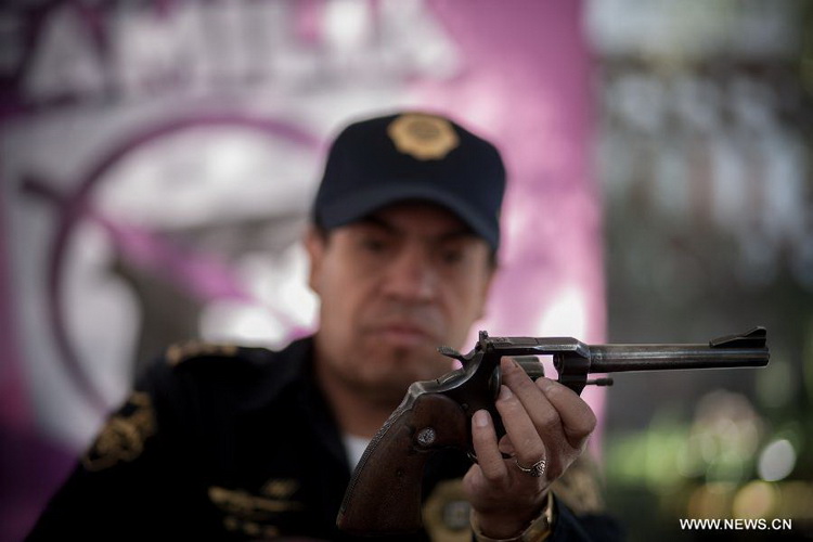 A Mexican Police officer inspects a weapon which is exchanged for groceries and cash by residents as part of "For your family, voluntary disarmament" program held at Iztapalapa Deputation, in Mexico City, capital of Mexico, on Dec. 27, 2012. (Xinhua/Pedro Mera)  