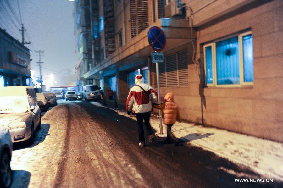 A man and his child go home hand in hand near the Heping Gate in Beijing, capital of China, Dec. 28, 2012. Beijing has witnessed the 7th snowfall in this winter on Friday. (Xinhua/Sun Ruibo)