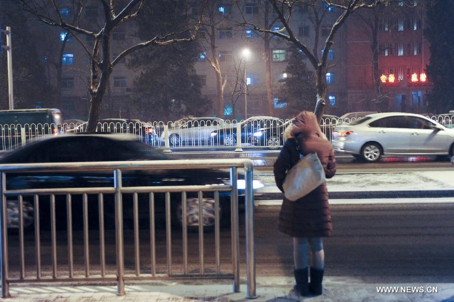 A citizen waits for the bus in snow near the Xuanwu Gate in Beijing, capital of China, Dec. 28, 2012. Beijing has witnessed the 7th snowfall in this winter on Friday. (Xinhua/Sun Ruibo)