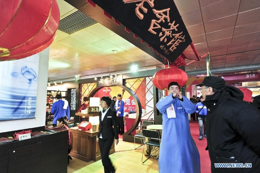 A staff member of Laoshe Teahouse (2nd R) does business promotions at the 2012 Beijing Tourism Product Expo in Beijing, capital of China, Dec. 28, 2012. The four-day expo was opened Friday at the China International Exhibition Center in Beijing. Tourism souvenirs, craftworks, business gifts, outdoor gears and cultural and creative products from about 1,000 exhibitors were demonstrated at the event. (Xinhua/Wang Jingsheng)