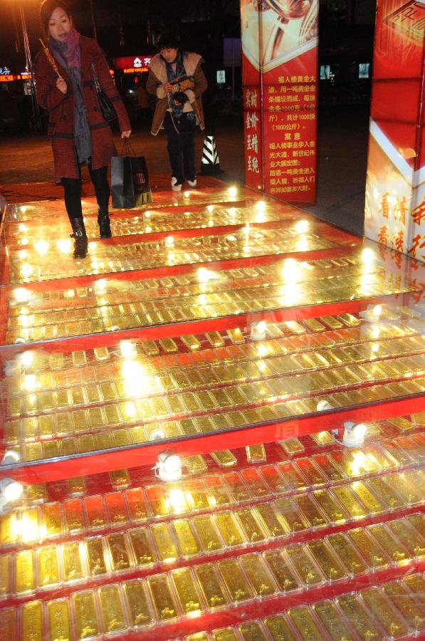 Citizens walk on the "gold road," on which 1,000 pieces of 1,000-gram gold bars are laid beneath toughened glass, in a gold shop in Binzhou City, east China's Shandong Province, Jan. 1, 2013. (Xinhua/Zhang Binbin)