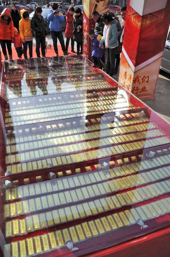 Citizens gather to watch the "gold road," on which 1,000 pieces of 1,000-gram gold bars are laid beneath toughened glass, in a gold shop in Binzhou City, east China's Shandong Province, Jan. 1, 2013. (Xinhua/Zhang Binbin)