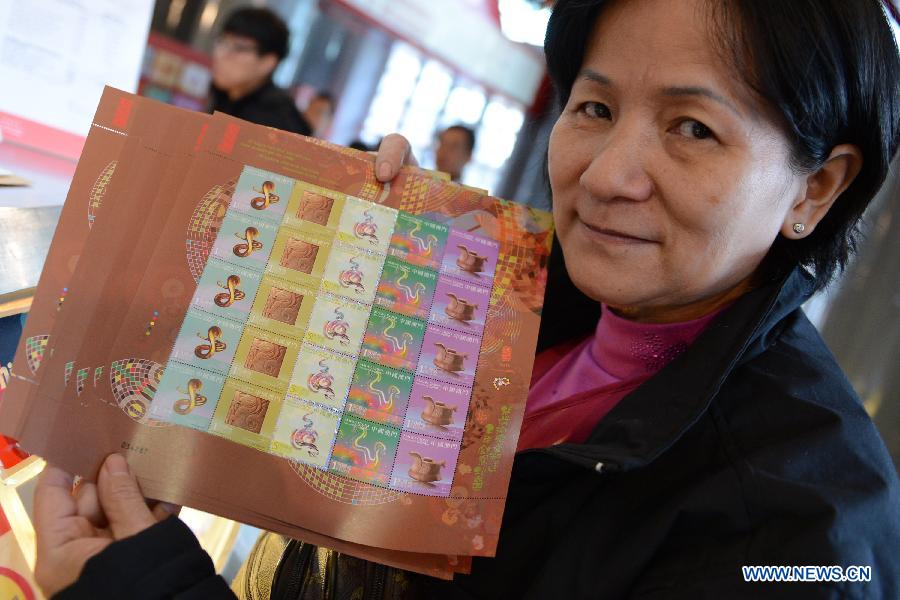 A citizen shows the newly-bought stamps featuring a cartoon snake at a post office in Macao, south China, Jan. 3, 2013. (Xinhua/Cheong Kam Ka)