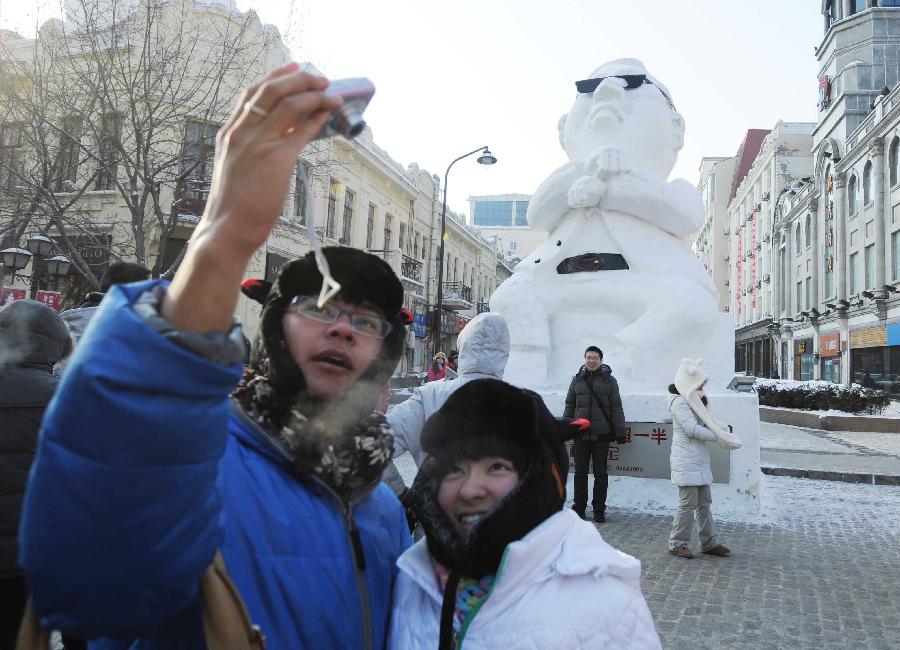 Tourists pose for photo in front of a snow sculpture of South Korean rapper Psy in Harbin, capital of northeast China's Heilongjiang Province, Jan. 2, 2013. Psy's music video of "Gangnam Style," featuring the horse-riding dance, became a global sensation this year. (Xinhua/Wang Jianwei)