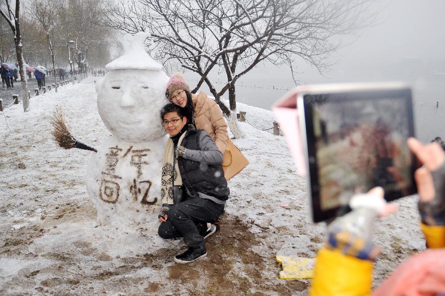 Tourists pose for photos before a snowman near the West Lake in Hangzhou, capital of east China's Zhejiang Province, Jan. 4, 2013. Citizens and tourists enjoyed the snow-covered landscape of West Lake here on Friday after northern and central Zhejiang received continuous snowfall since this Thursday. (Xinhua/Huang Zongzhi)
