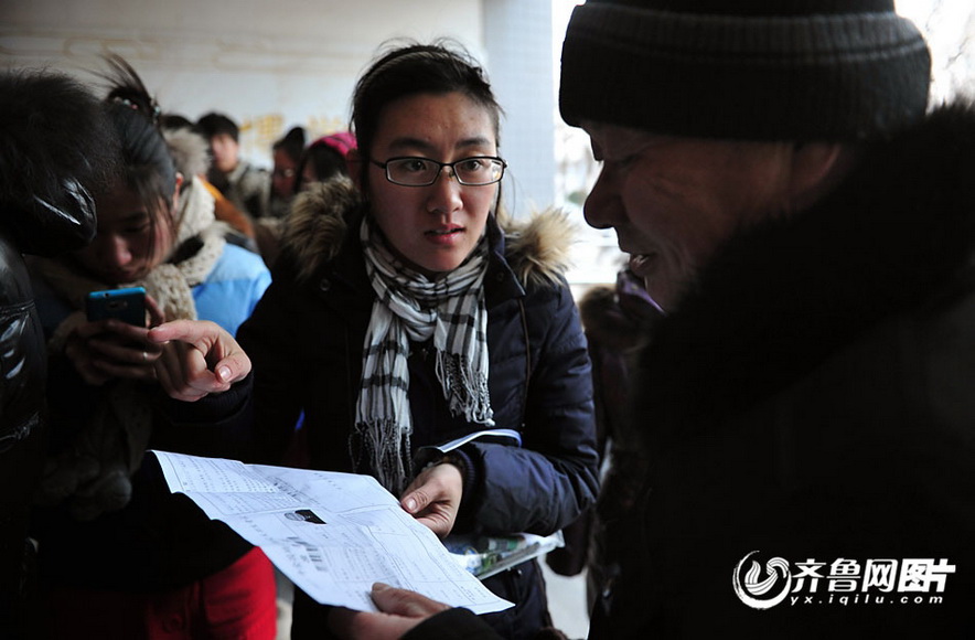 Zhang Shangxue, with admission card in hand, asks young candidate about information of exam room on Jan. 5, 2012. (Photo/yx.iqilu.com)