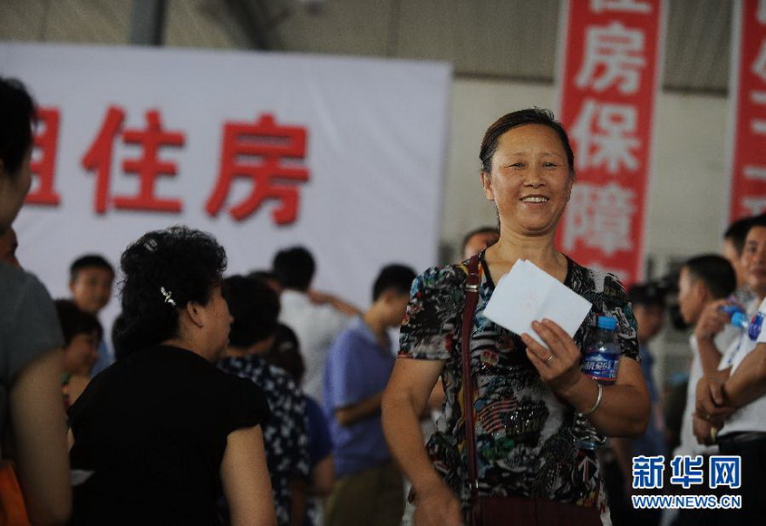 Low-rent housing: An applicant holding the “Low-Rent Housing Agreement” waits for picking a number in a low-rent housing service in Jintang, Chengdu on July 28, 2012. 21 rural households are allocated low-rent houses through lottery number. The government planned to construct 7 million units of low-income houses in 2012 and 17 million units are under construction. (Xinhua/Li Qiaoqiao)