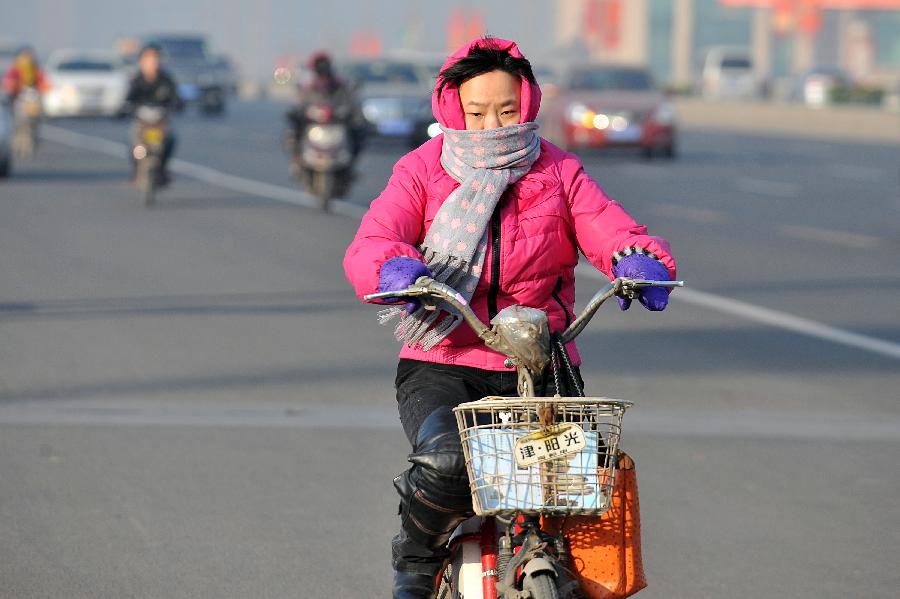 A woman dressing in warm clothes rides a bike in Taiyuan, north China's Shanxi Province, Jan. 5, 2013. Jan. 5 is the Slight Cold, the 23rd solar term according to the traditional Chinese lunar calendar, ushering in the coldest period in China. (Xinhua/Zhan Yan)  