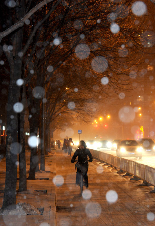 People travel in snow-covered street near the east third ring road in Beijing, Dec. 28, 2012. Beijing witnessed its 7th snowfall this winter. (Xinhua/Luo Xiaoguang)
