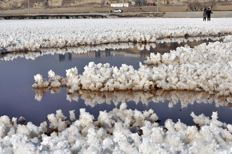 Two visitors watch the sodium sulfate generated on the surface of Yuncheng Salt Lake, Shanxi province, Dec. 30, 2012. (Xinhua/Huang Wenpeng)