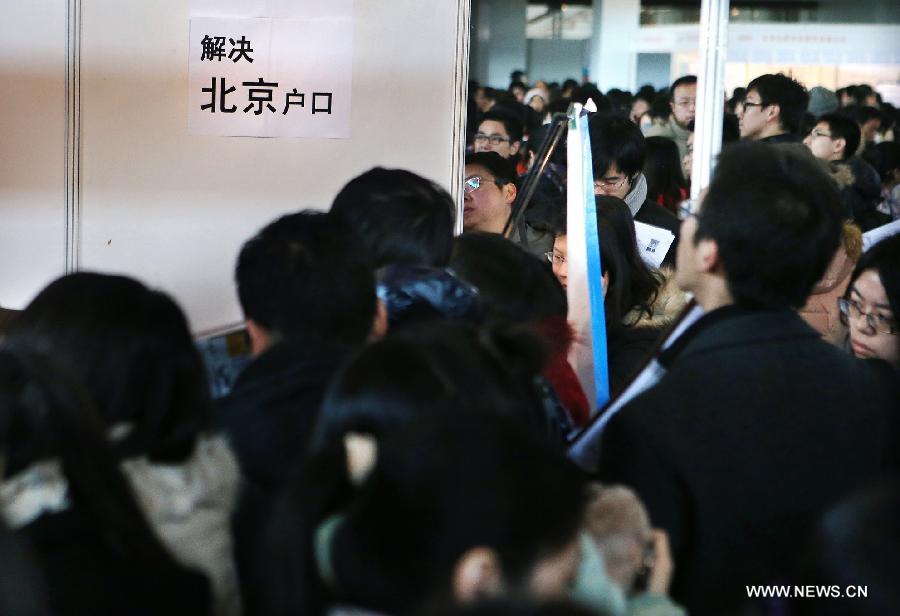 Job seekers view a recruit advertisement promising to help employees to get local household registration in Beijing, or "hukou," at a pavilion of a job fair held at China International Exhibition Center in Beijing, China, Jan. 6, 2013. The job fair, held for postgraduates, provided 18,000 job vacancies and was expected to attract 40,000 job seekers. (Xinhua/Wan Xiang) 