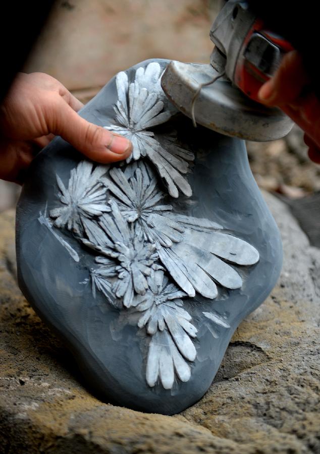 A craftsman named Qian Daishou polishes a semi-finished handicraft made of chrysanthemum stone in a workshop in Enshi, central China's Hubei Province, Jan. 12, 2013.(Xinhua/Song Wen) 