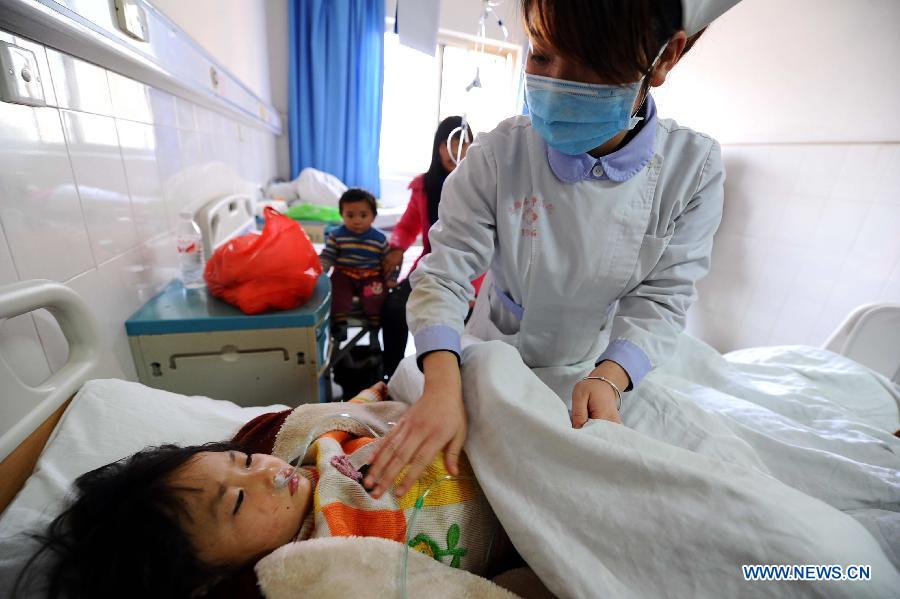A nurse takes care of a child injured in an accident on an express way in Xifeng county, southwest China's Guizhou Province, Jan. 13, 2013. Five people died and 19 others were injured after a coach collided with a guardrail and rolled over around 5 a.m. Sunday. (Xinhua) 