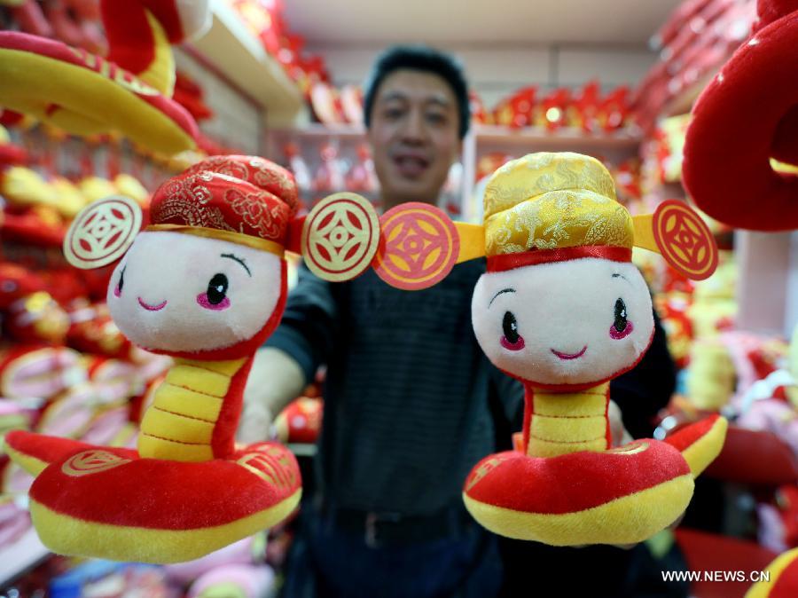 A man displays two cartoon figures of snakes at Tianyi small commodities market in Beijing, capital of China. Jan. 13, 2013. The coming lunar new year, which falls on Feb. 10, 2013, marks the Year of Snake on the Chinese Zodiac.(Xinhua/Luo Wei)