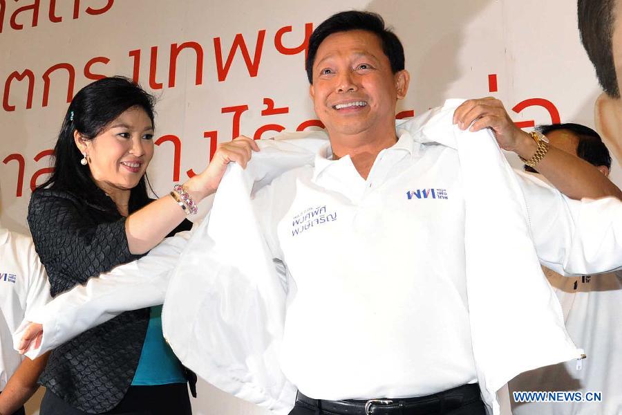 Thai Prime Minister Yingluck Shinawatra (L) puts on clothes for Bangkok Governor Candidate Pol Gen Pongsapat Pongcharoen at the Pheu Thai party headquarters in Bangkok, Thailand, Jan. 15, 2013. The Pheu Thai Party unveiled Bangkok Governor Candidate on Tuesday.(Xinhua/Rachen Sageamsak)