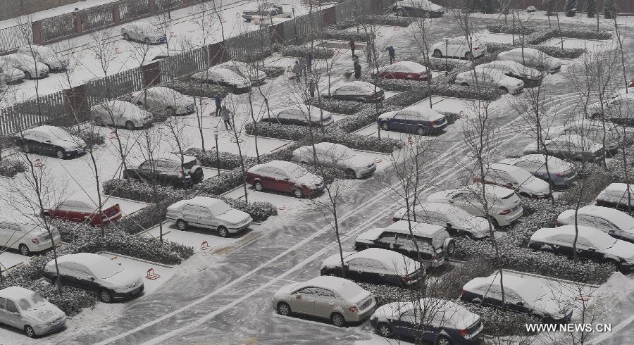 People clear off snow at a parking lot in Beijing, capital of China, Jan. 20, 2013. Snowfall here relieves the air pollution but affects the local traffic in the city. (Xinhua/Jin Liwang)  