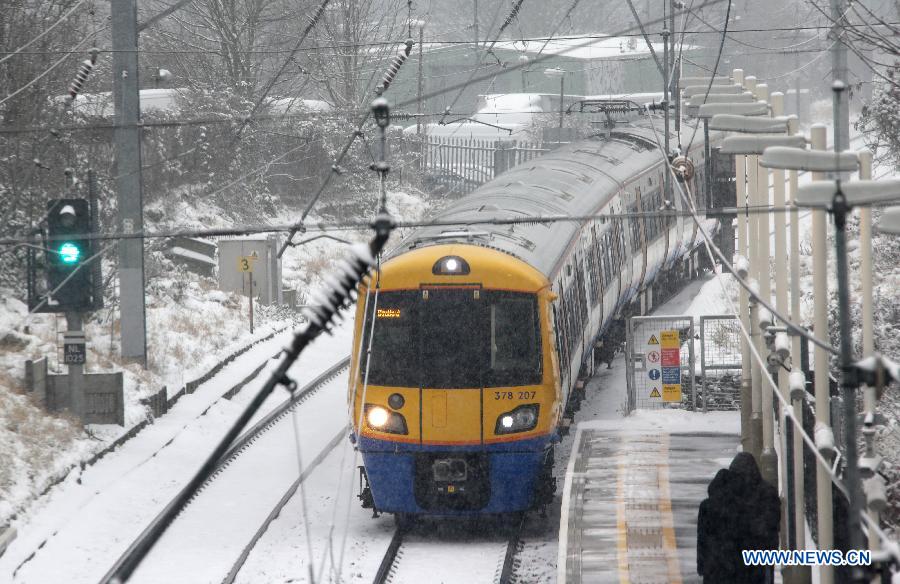 A train travels in the snow in London, Britain, Jan. 20, 2013. (Xinhua/Yin Gang)