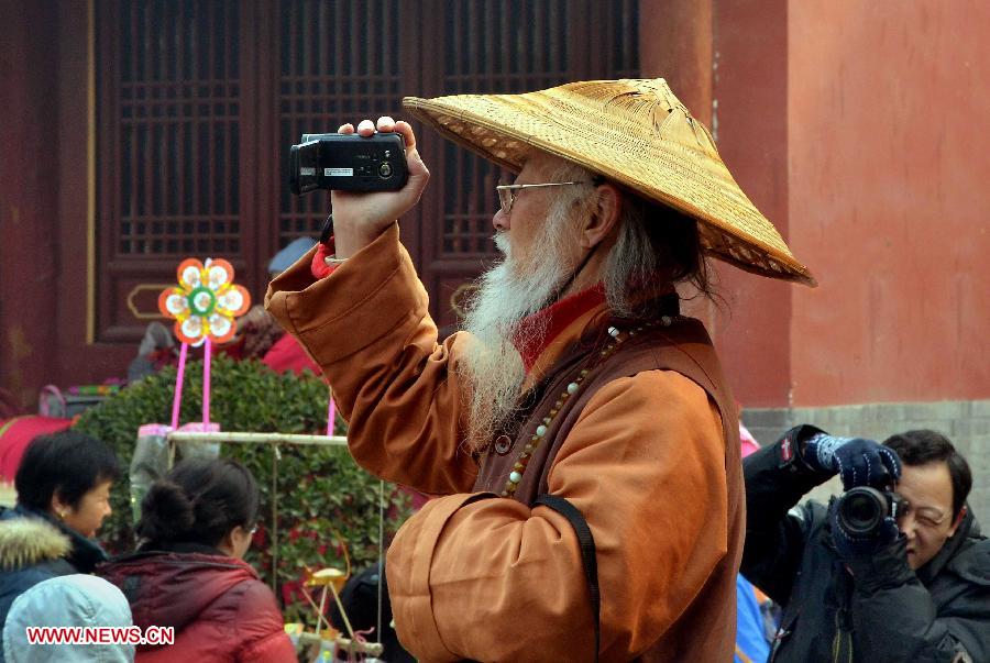 File photo taken on Jan. 23, 2012 shows a visitor films temple fair activities in Zhengzhou, capital of central China's Henan Province. Temple fair in central China area is an important social activity for local people. The ancient temple fairs in central China were ceremonious sacrificial rituals. As time goes by, the focus of temple fair activities has shifted from "gods" to "people". The modern temple fair in central China is a platform of displaying folk culture as well as a channel for commodity circulation. According to statistics from the provincial cultural sector, there are about 35,000 temple fairs each year in Henan. (Xinhua/Wang Song)