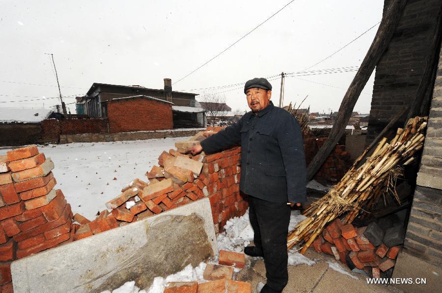 A villager points to a brick wall destroyed by an earthquake in Haozitun Village of Liutiaozhai Township in county-level city of Dengta, northeast China's Liaoning Province, Jan. 23, 2013. A 5.1-magnitude earthquake jolted the border region of Dengta and Shenyang cities in Liaoning at 12:18 p.m. (0418 GTM) on Wednesday. The epicenter, with a depth of about 7 kilometers, was located near Dengta and the Sujiatun District of Shenyang, capital of Liaoning Province, at 41.5 degrees north latitude and 123.2 degrees east longitude. Liu Wenlong, mayor of Dengta, said the city government has not received any reports about casualties or house collapse. No casualties or house collapses have been reported yet. (Xinhua/Yang Qing)