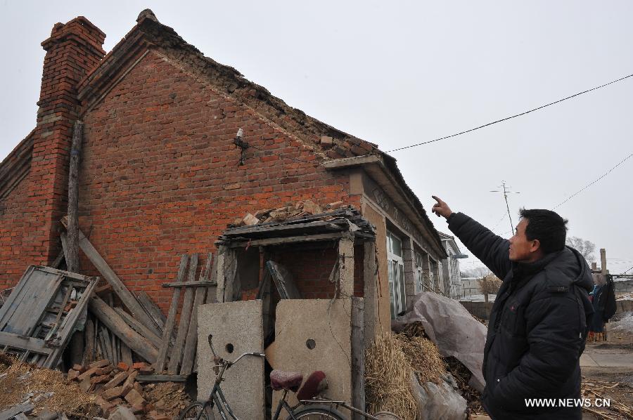 A man points to the house roof destroyed in an earthquake at Shubeitai Village of Liutiaozhai Township in county-level city of Dengta, northeast China's Liaoning Province, Jan. 23, 2013. A 5.1-magnitude earthquake jolted the border region of Dengta and Shenyang cities in Liaoning at 12:18 p.m. (0418 GTM) on Wednesday, the China Earthquake Networks Center has said. The epicenter, with a depth of about 7 kilometers, was located near Dengta and the Sujiatun District of Shenyang, capital of Liaoning Province, at 41.5 degrees north latitude and 123.2 degrees east longitude. Liu Wenlong, mayor of Dengta, said the city government has not received any reports about casualties or house collapse. But cracks were spotted in houses in some townships. No casualties or house collapses have been reported in Sujiatun either. (Xinhua/Zhao Jianjun) 