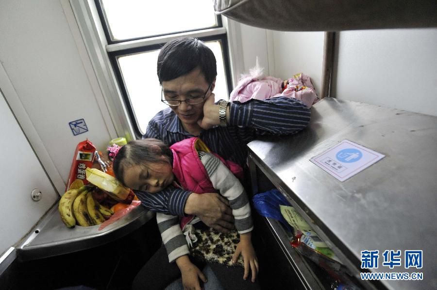 A girl falls asleep in arms of her father in a narrow corner surrounded by washing basin and dust bin aboard a train heading to Chongqing, which is the destination of their journey, Jan. 17, 2013. (Photo/Xinhua)