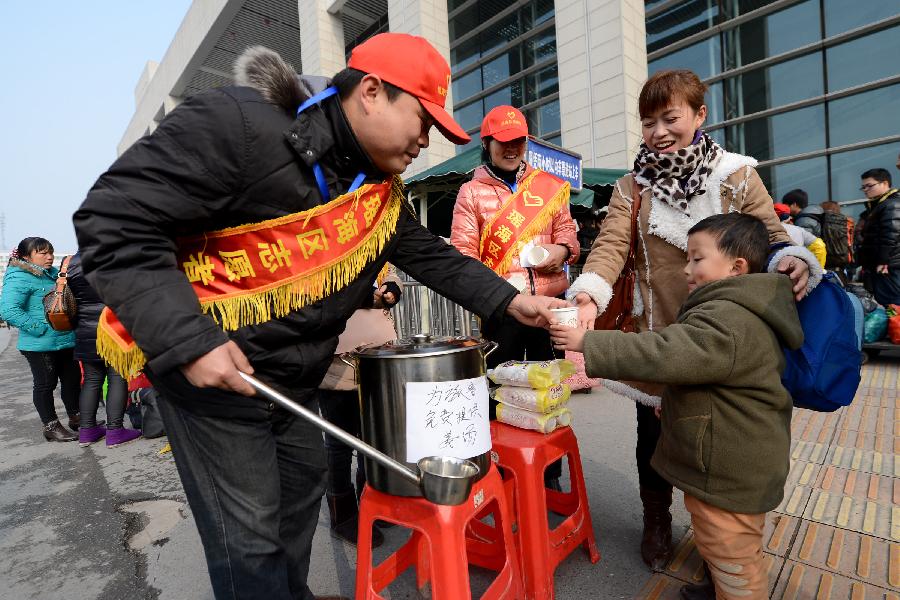 Volunteers offer hot ginger beverage to the passengers at Hefei Train station in Hefei, capital of east China's Anhui Province, Jan. 23, 2013. A total of 100 volunteers began their work at Hefei train station to help the passengers in the Spring Festival travel peak. (Xinhua/Zhang Duan)
