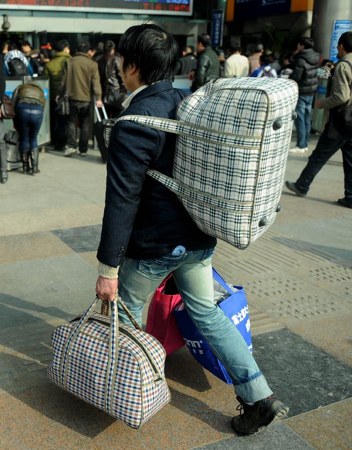 A man carries his luggage on the square of the train station in Chengdu, capital of southwest China's Sichuan Province, Jan. 24, 2013. As the spring festival approaches, more than more people started their journey home. (Xinhua/Xue Yubin)