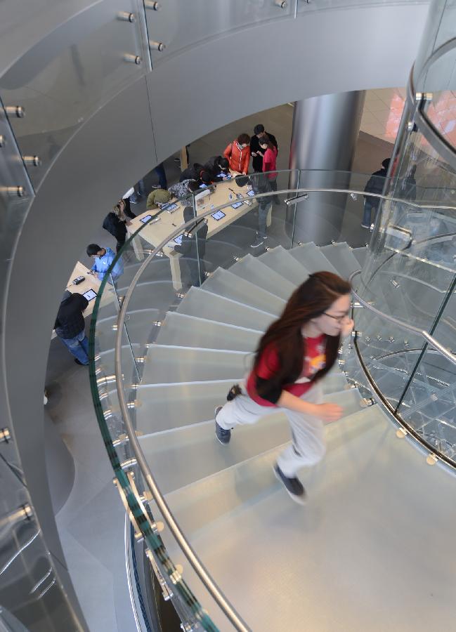 A working staff walks upstairs to fetch apple products for customers at Wangfujin Apple Store in Beijing, capital of China, Jan. 25, 2013. Apple Store held a sales activity on Friday, during which customers could enjoy special pricing online and at Apple retail stores on apple products. (Xinhua/Qi Heng) 
