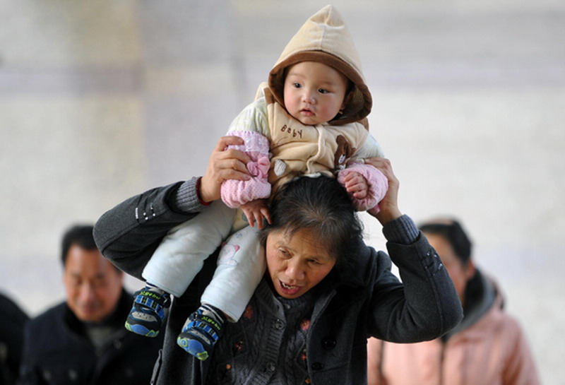 A woman carries a baby on her shoulder at Changsha Railway Station, Jan 26, 2013.  (Photo/Xinhua)