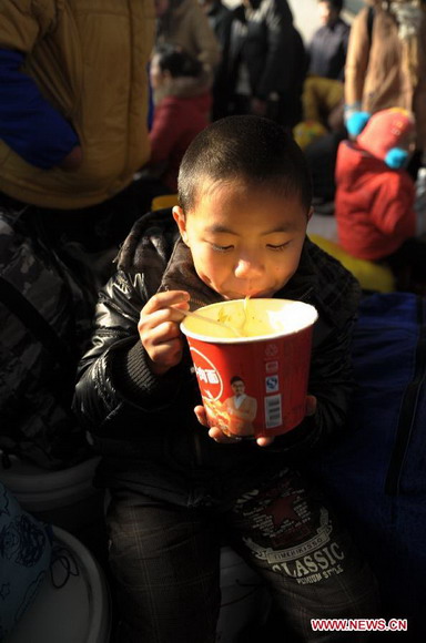 A child eats instant noodles at the waiting hall of railway station in Yuyao City, east China's Zhejiang Province, Jan. 26, 2013. The 40-day Spring Festival travel rush started Saturday. (Xinhua/Zhang Hui) 