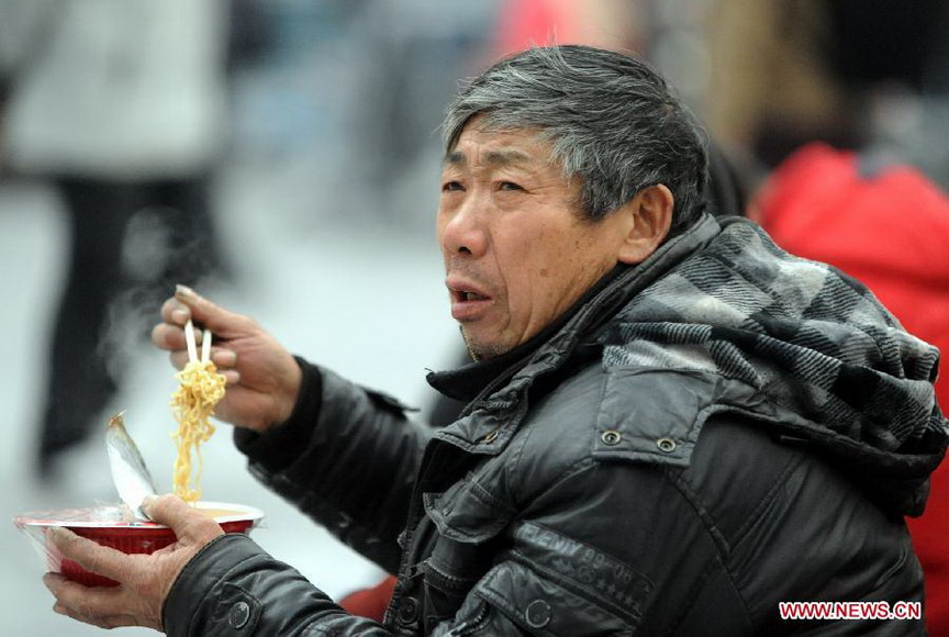 A passenger eats instant noodles at the waiting hall of railway station in Shenyang, capital of northeast China's Liaoning Province, Jan. 26, 2013. The 40-day Spring Festival travel rush started Saturday. (Xinhua/Yang Xinyue)