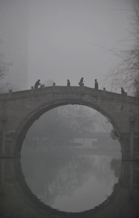 Citizens walk on a bridge amid heavy fog in Hangzhou, capital of east China's Zhejiang Province, Jan. 28, 2013. The provincial meteorological observatory has issued an orange-coded alert on Jan. 28 morning as foggy weather here cut visibility to less than 500 meters and worsened air pollution in many cities. (Xinhua/Huang Zongzhi) 