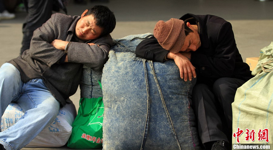 Tried travelers: Two travelers fall asleep at the square of Hankou Railway Station on Jan. 26, 2013. (CNS/Zhang Chang)
