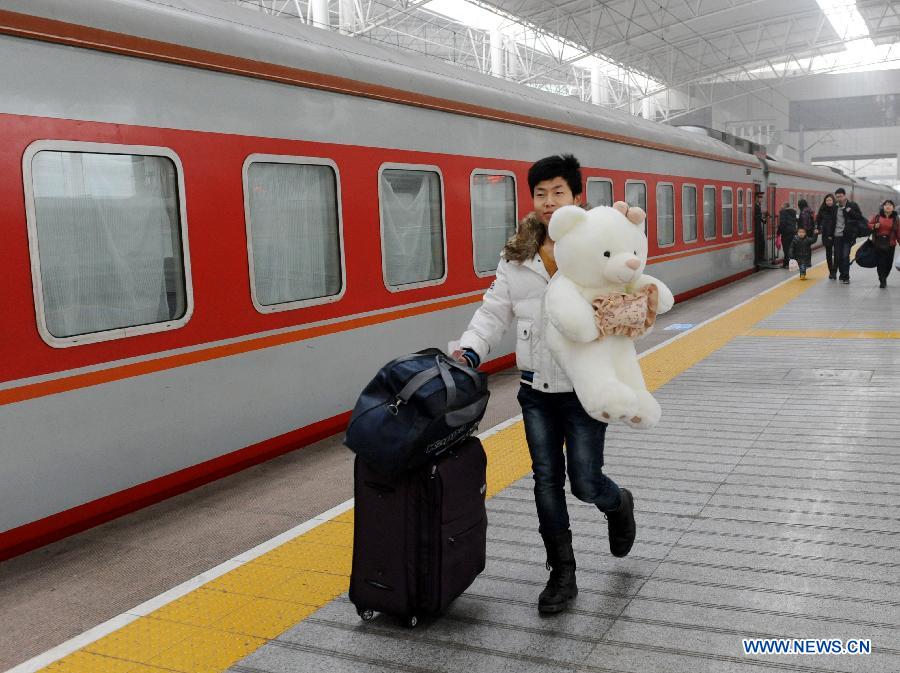 A passenger holding a gift for his friend prepares to board the train at the Zhengzhou Railway Station in Zhengzhou, capital of central China's Henan Province, Jan. 30, 2013. The 40-day Spring Festival travel rush started on Jan. 26. The Spring Festival, which falls on Feb. 10 this year, is traditionally the most important holiday of the Chinese people. It is a custom for families to reunite in the holiday, a factor that has led to massive seasonal travel rushes in recent years as more Chinese leave their hometowns to seek work elsewhere. Public transportation is expected to accommodate about 3.41 billion travelers nationwide during the holiday, including 225 million railway passengers.(Xinhua/Li Bo)