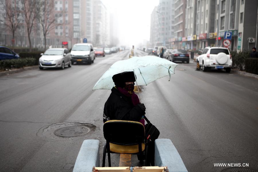 A traffic coordinator sits on a road in Beijing, capital of China, Jan. 31, 2013. Light snow hit parts of the city on Thursday and the local meteorological observatory issued a yellow alert for icy road. (Xinhua/Jin Liwang) 