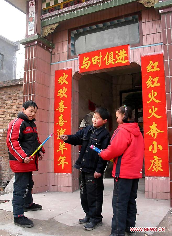 Children set off fireworks in front of a front door pasted with spring couplet in Shuidihe Village of Gongyi City, central China's Henan Province, Feb. 3, 2003. To paste spring couplet is one of the most important custom in the central China's region. The spring couplet, a New Year's decoration, expresses happy and hopeful thoughts for the coming year. Chinese people who live in the central China region have formed various traditions to celebrate the Chinese Lunar New Year. (Xinhua/Wang Song)