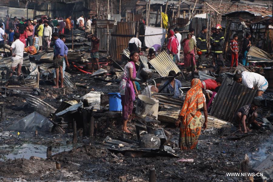 People gather around the site of a fire accident in a slum in Dhaka, Bangladesh, Feb. 3, 2013. About 100 shanties were destroyed in the accident, official said. (Xinhua/Shariful Islam)