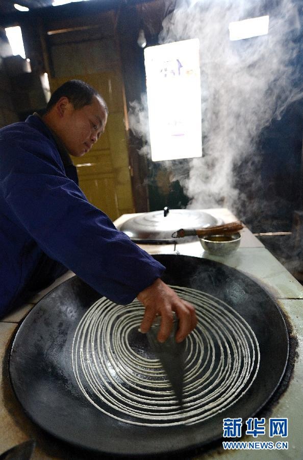 A man is cooking bean pancake. According to the traditional custom, people prepare special foods such as glutinous rice cake, soybean and corn candy in Xuanen County, Hubei province. (Xinhua/ Fang Dehua)