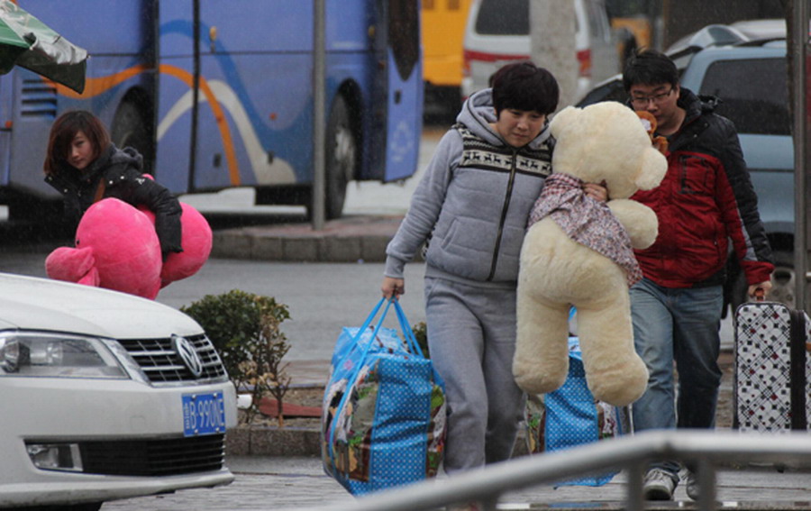 Two women hold toy bears at a bus station in Qingdao, East China's Shandong province on Jan 3, 2013. (Photo/Xinhua)