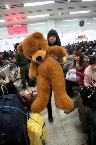 A woman walks with a big toy bear at Yantai Railway Station in East China's Shandong province on Feb 3, 2013 (Photo/Xinhua)