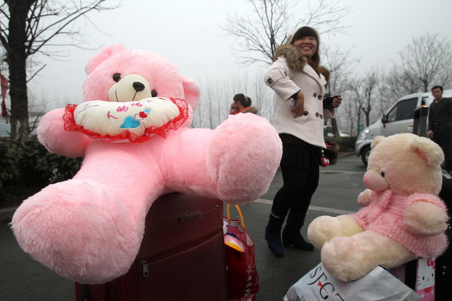 Two women hold toy bears at a bus station in Qingdao, East China's Shandong province on Jan 3, 2013. (Photo/Xinhua) 
