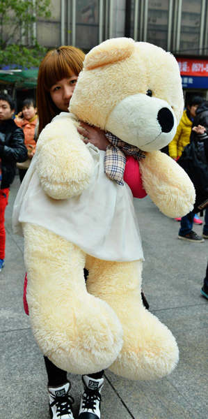 A woman poses with a toy bear at Hangzhou Railway Station in East China's Zhejiang province on Feb 3, 2013. (Photo/Xinhua)